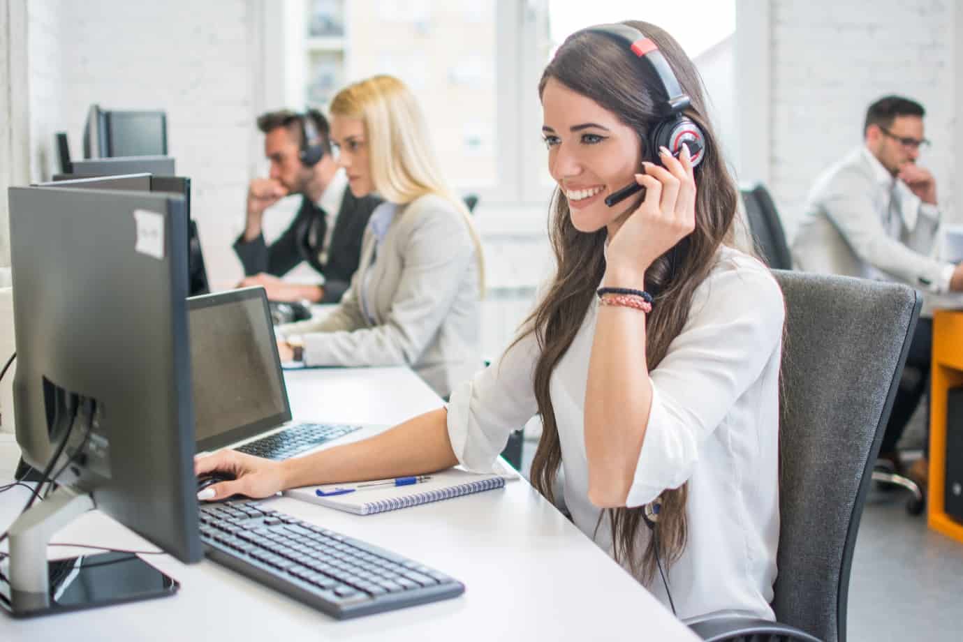 smiling woman call center operator with headset using computer at office