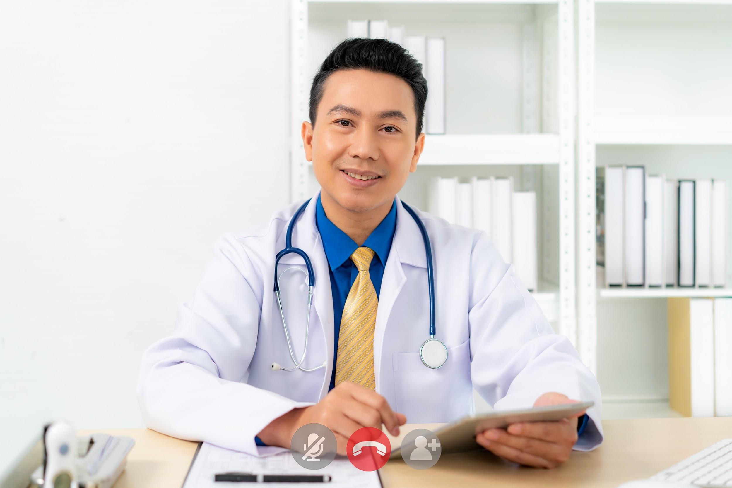 Smiling Asian doctor with digital tablet looking at camera.