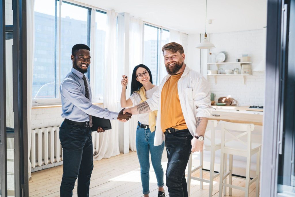 Black realtor and happy couple sealing deal by shaking hands